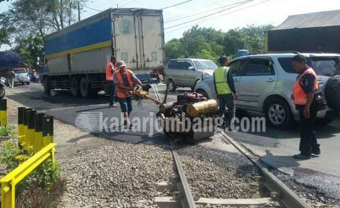 Pekerja tampak sibuk melakukan penambalan jalan