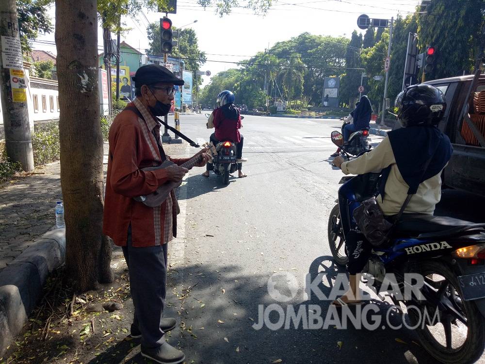 Mbah Ajijan saat beraksi dengan alat gitar kentrungnya di area traffic light di Jombang.