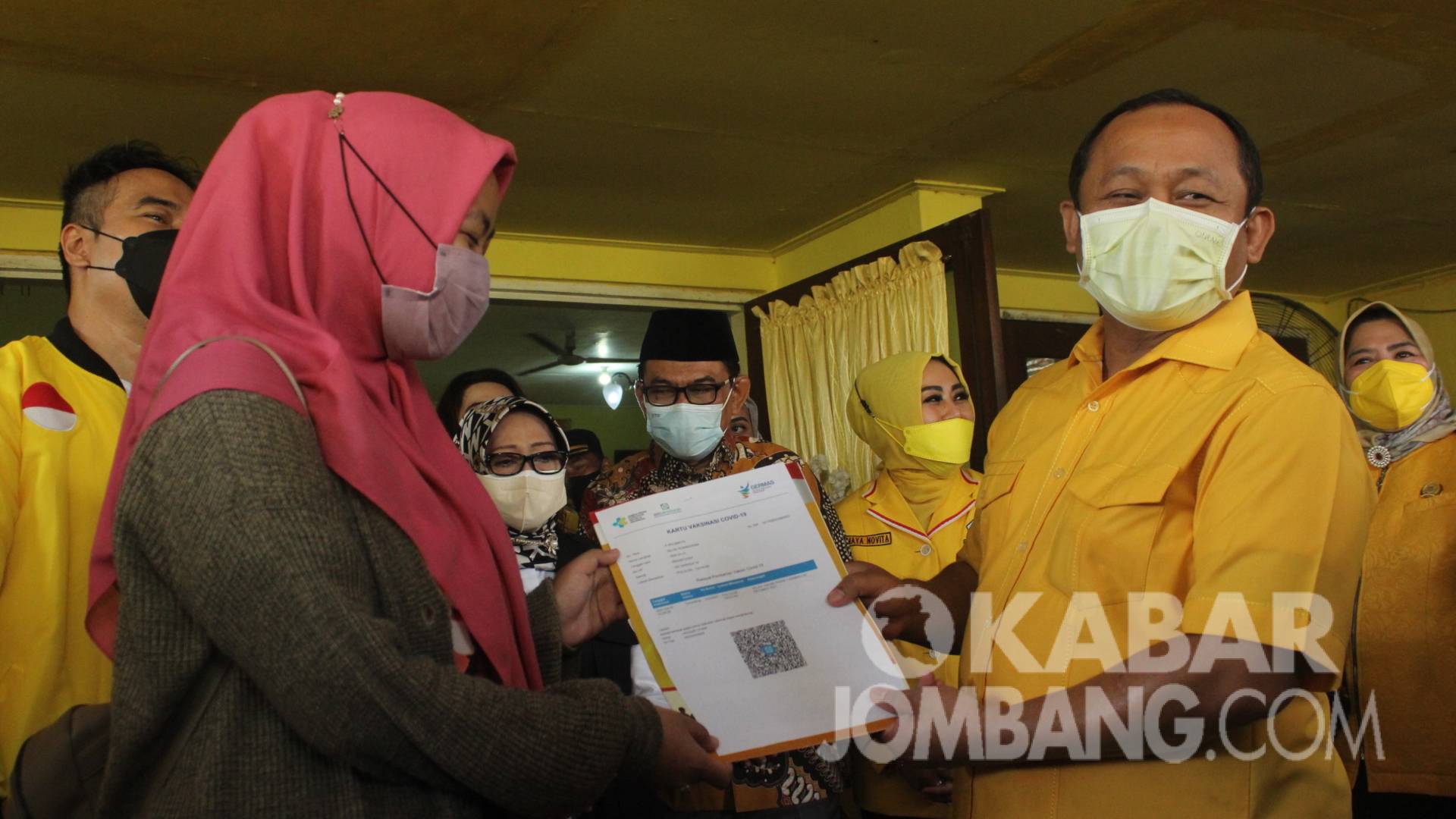 Ketua DPD Golkar Provinsi Jawa Timur, Sarmuji (kanan) menyerahkan secara simbolis kartu vaksin covid-19 kepada peserta di DPD Partai Golkar Jombang, Sabtu (25/9/2021). KabarJombang.com/Daniel Eko/